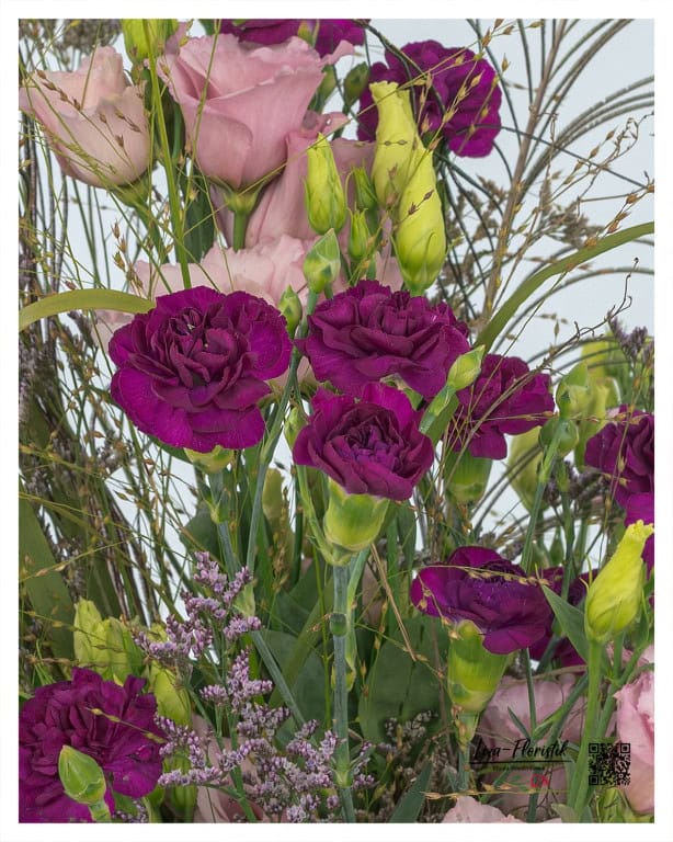 Close-up of the magnificent arrangement with deep purple carnations and delicate pink lisianthus, complemented by fine grasses - a harmonious play of colors and textures.