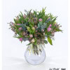 Bouquet with purple tulips, delicate wax flowers and eucalyptus branches arranged with fresh greenery.
