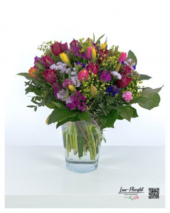 A lively spring bouquet with a harmonious mix of red, yellow and pink tulips, delicate gypsophila flowers, violet statice, bright lady's mantle and lush green eucalyptus - a colorful arrangement full of freshness and joy of life.