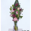 Modern bouquet with pink ranunculus, purple carnations, colored ammi and delicate tulips, combined with decorative cherry branches and a large strelitzia leaf as a background.