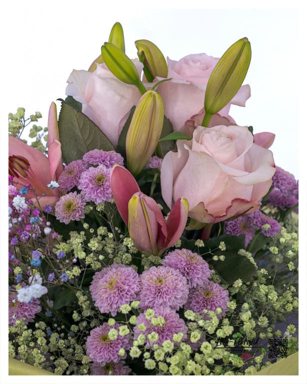 Close-up of the birthday bouquet with delicate pink roses, half-opened pink lilies, purple chrysanthemums and fine gypsophila - the structured variety of flowers and the harmonious play of colors are particularly visible in detail.