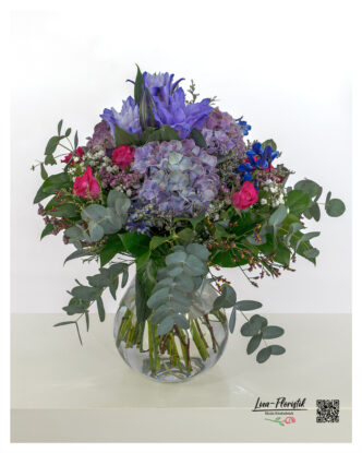 Lush bouquet of flowers with purple hydrangeas, pink roses, purple lilies, blue delphiniums, gypsophila, statice and fresh eucalyptus - ideal as a gift or decoration.