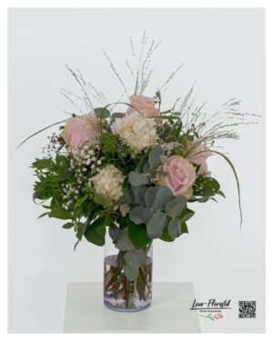 Lush bouquet of delicate pink roses, cream-colored hydrangea, delicate ornamental grass, white gypsophila and green privet berries