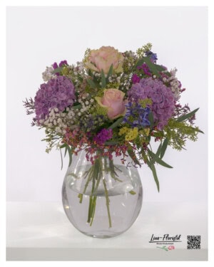Impressive bouquet of flowers with roses, purple hydrangeas, airy gypsophila, eucalyptus, statice, thistles and bright delphiniums.