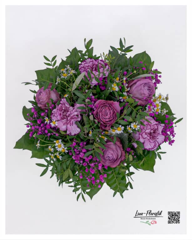 Close-up of velvety purple roses and delicate carnations in a hand-tied bouquet