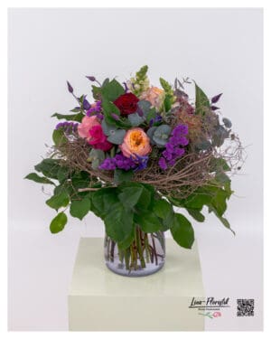 Creatively tied bouquet with colorful premium roses and clematis – featuring snapdragons, statice, thistles, and decorative woven accents.