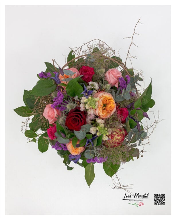 Top view of the arrangement – different rose colors, clematis, and thistles in a creative, artistic composition.