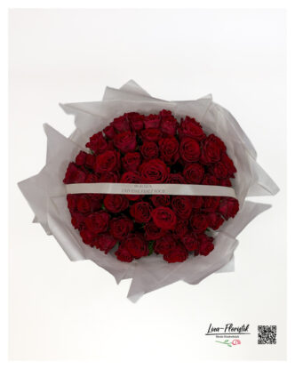 Round hand-tied rose bouquet in white tissue paper with a printed ribbon – top view.