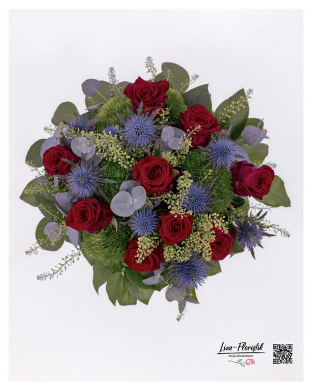 Scene view of the arrangement – red roses and blue eryngium in a harmonious, rounded composition.