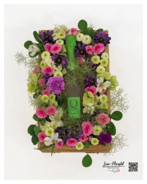 Floral arrangement in a rustic wooden crate with sparkling wine, pink roses, purple flowers, cream Santini chrysanthemums and delicate smokebush